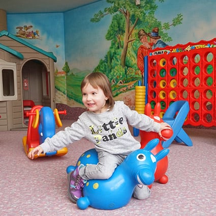 Sala giochi per bambini – ragazza su cavallo gonfiabile da rodeo, vacanza in famiglia